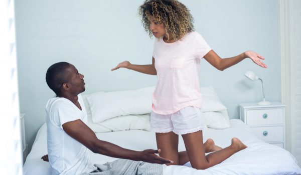 Young couple arguing on bed in bedroom